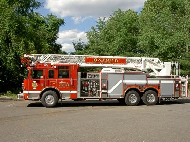 Driver-side profile showing ladder bed, side compartments, and rear axles