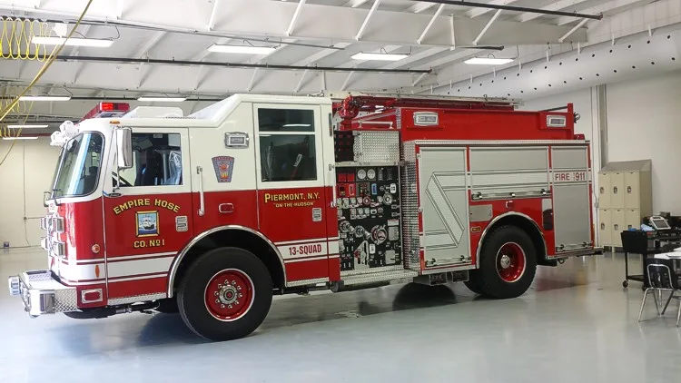 Driver-side full profile showing exposed pump panel controls, side compartments, and rear wheel area.