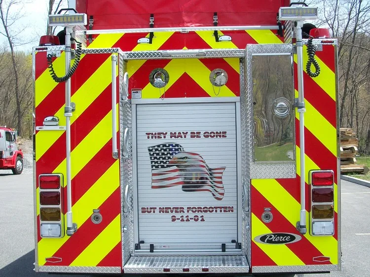 Rear close-up view with red-yellow chevrons, rear roll-up door graphic, and scene lights.