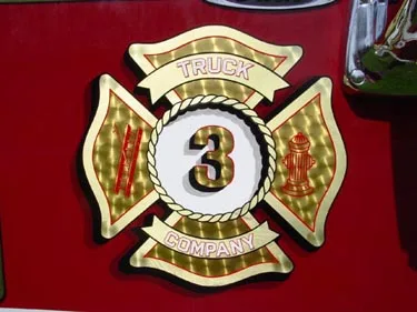 Maltese-cross badge close-up showing Truck 3 Company emblem