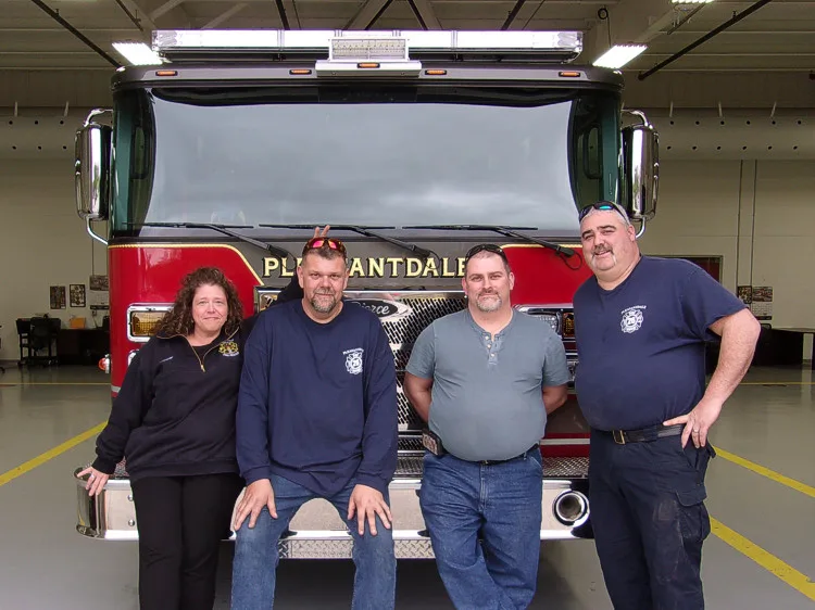 Group photo in front of open rear compartment and apparatus bay