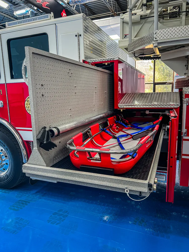 Open side compartment showing stacked hose trays and equipment storage