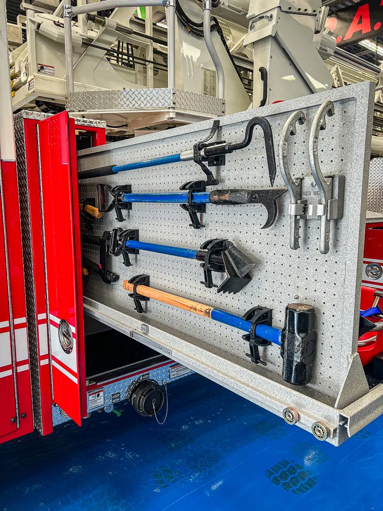 Open side compartment showing mounted nozzles, fittings, and hand tools