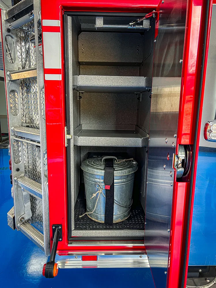 Open tall compartment showing shelves, pail storage, and lower equipment area