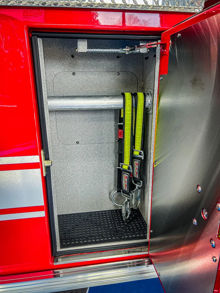 Open narrow compartment showing long-handled tools and side wall mounts