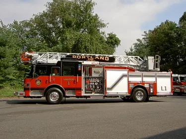 Full left-side profile of the aerial ladder truck with pump panel section and rear body compartments.