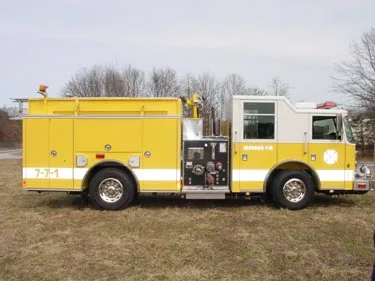 Driver-side profile view showing exposed pump panel, side compartments, and wheel area