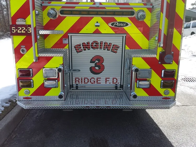 Straight rear view with red-yellow chevrons, rear roll-up door, and tailboard on one pumper.