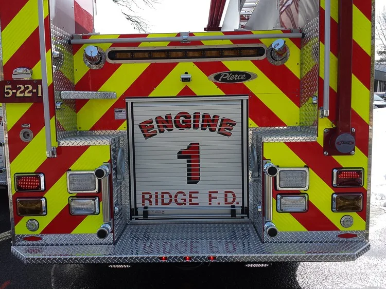 Straight rear view with red-yellow chevrons and rear roll-up door on the second pumper.