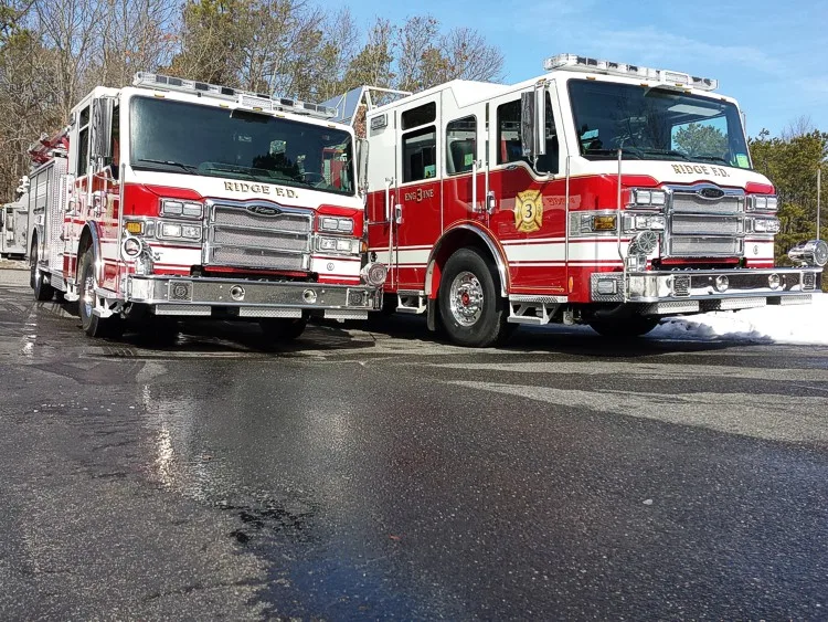 Wide front view of two parked pumpers showing both cabs, bumpers, and front wheel areas.