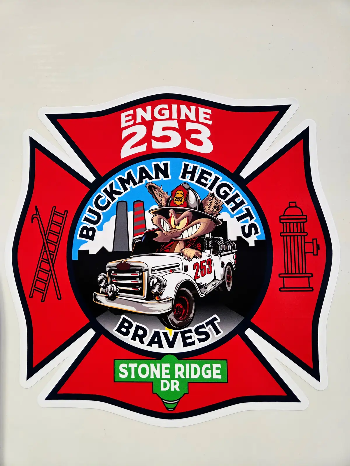 Maltese-cross style emblem decal close-up with cartoon engine and street-sign graphic