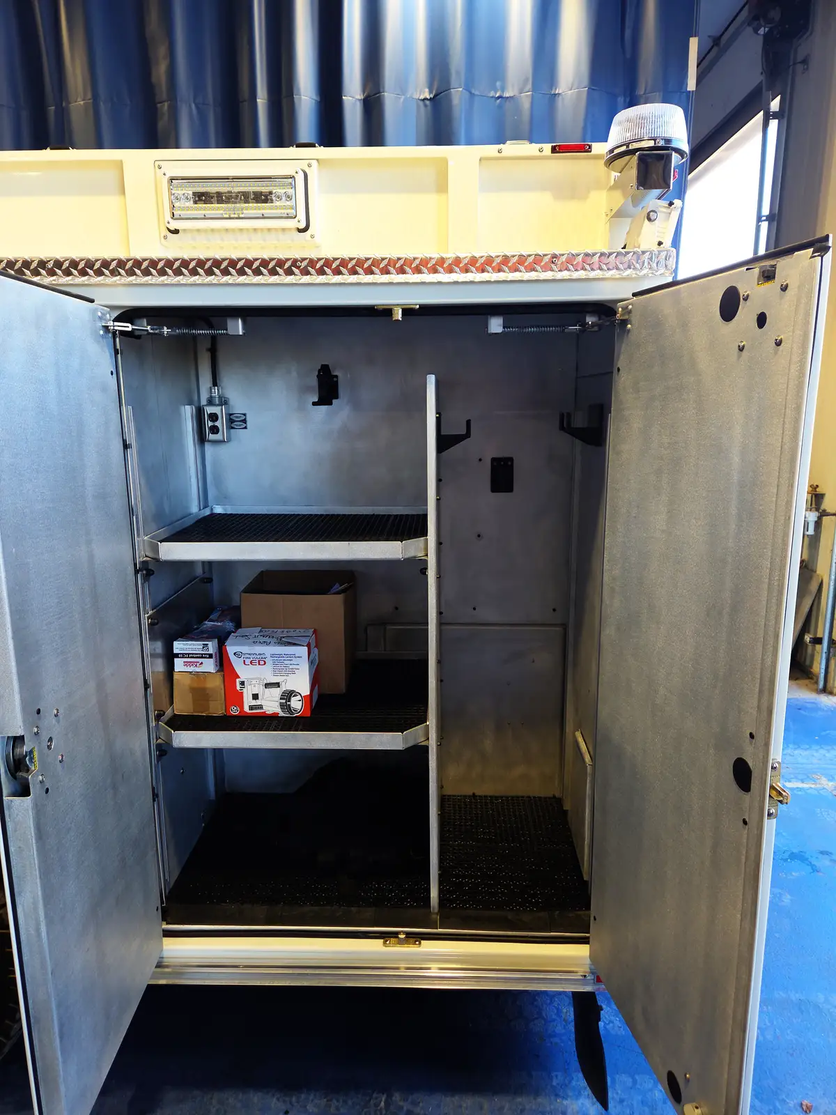 Open rear body compartment showing vertical divider, shelves, and empty storage bays