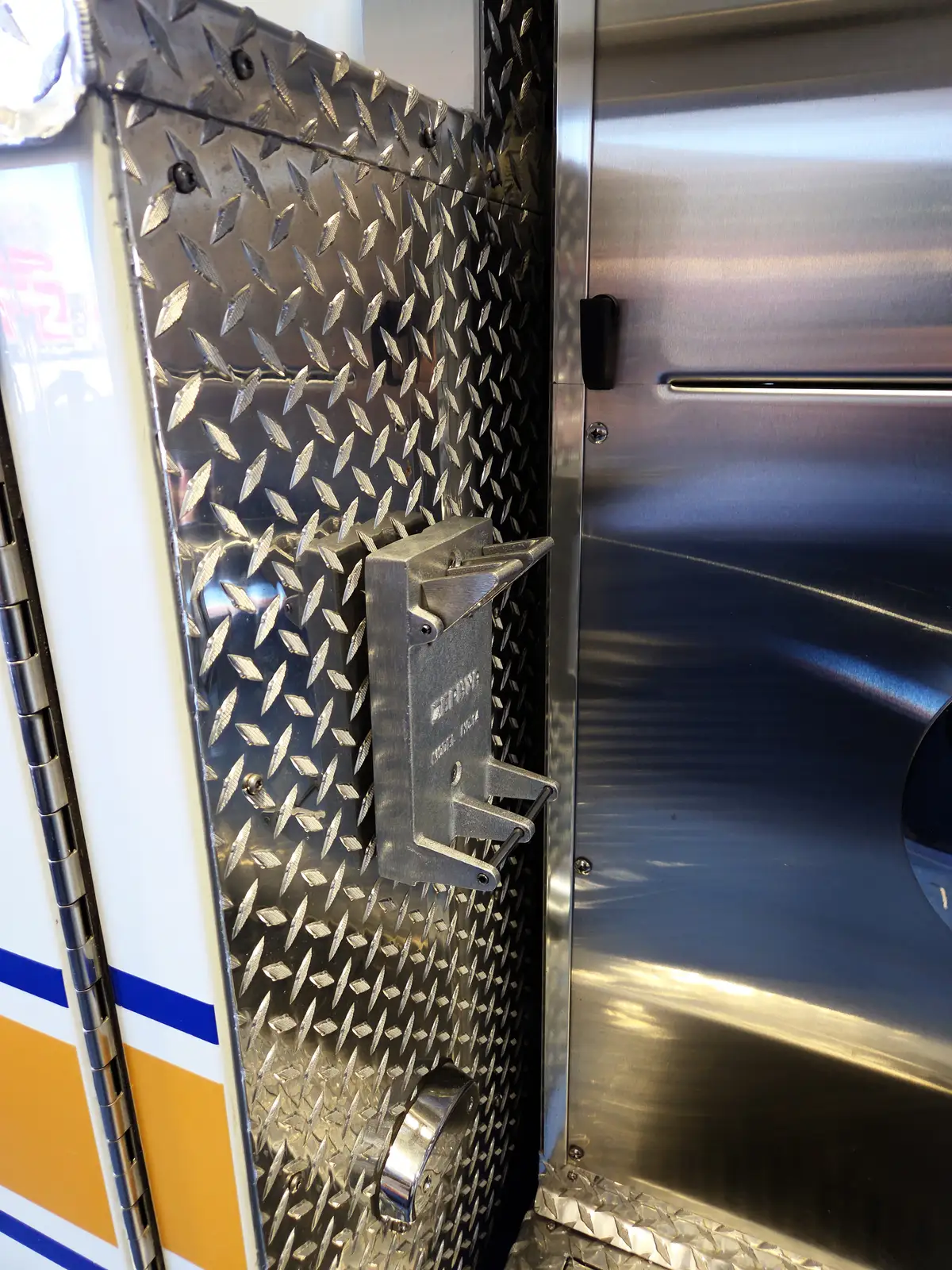 Diamond-plate body close-up showing mounted bracket and adjacent compartment panel