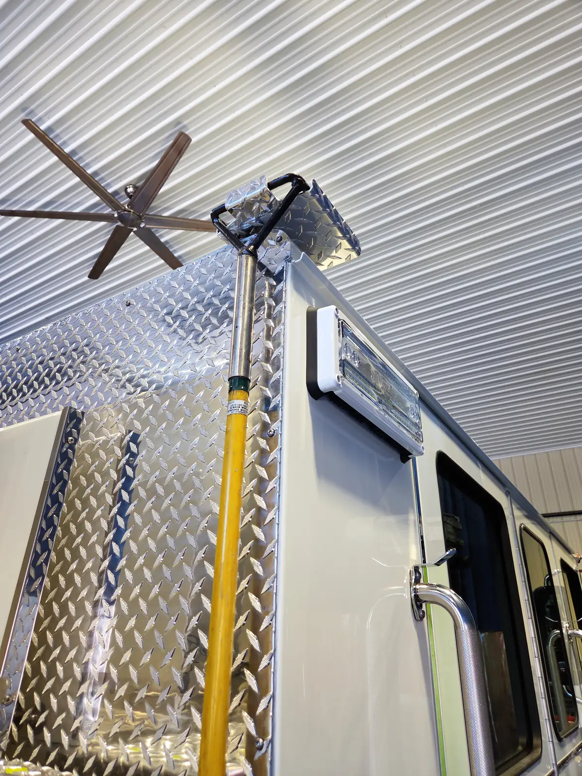 Upper body corner close-up showing mounted pike pole and warning light