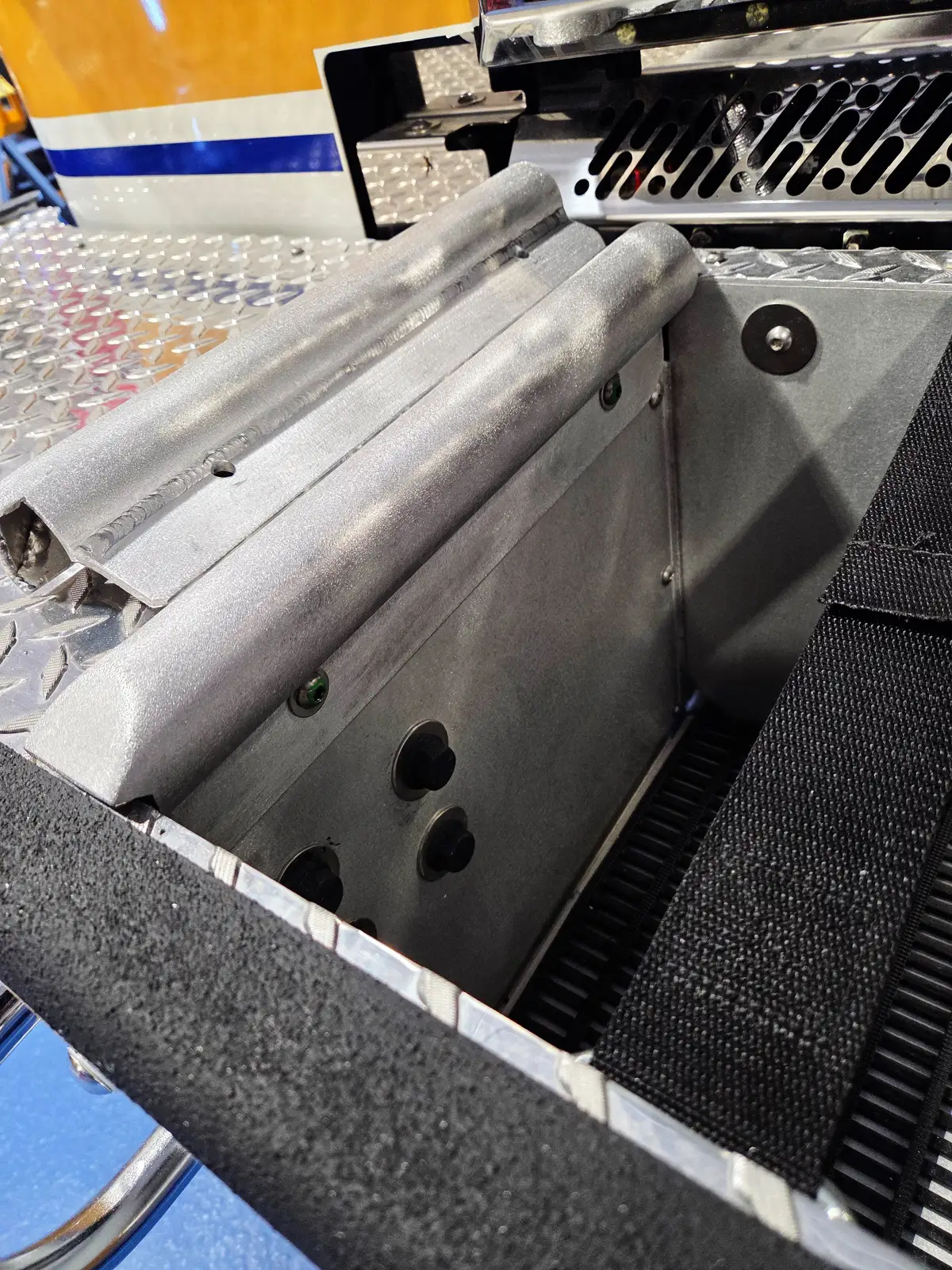 Open shallow storage bin close-up showing interior mounts and tool tray edge