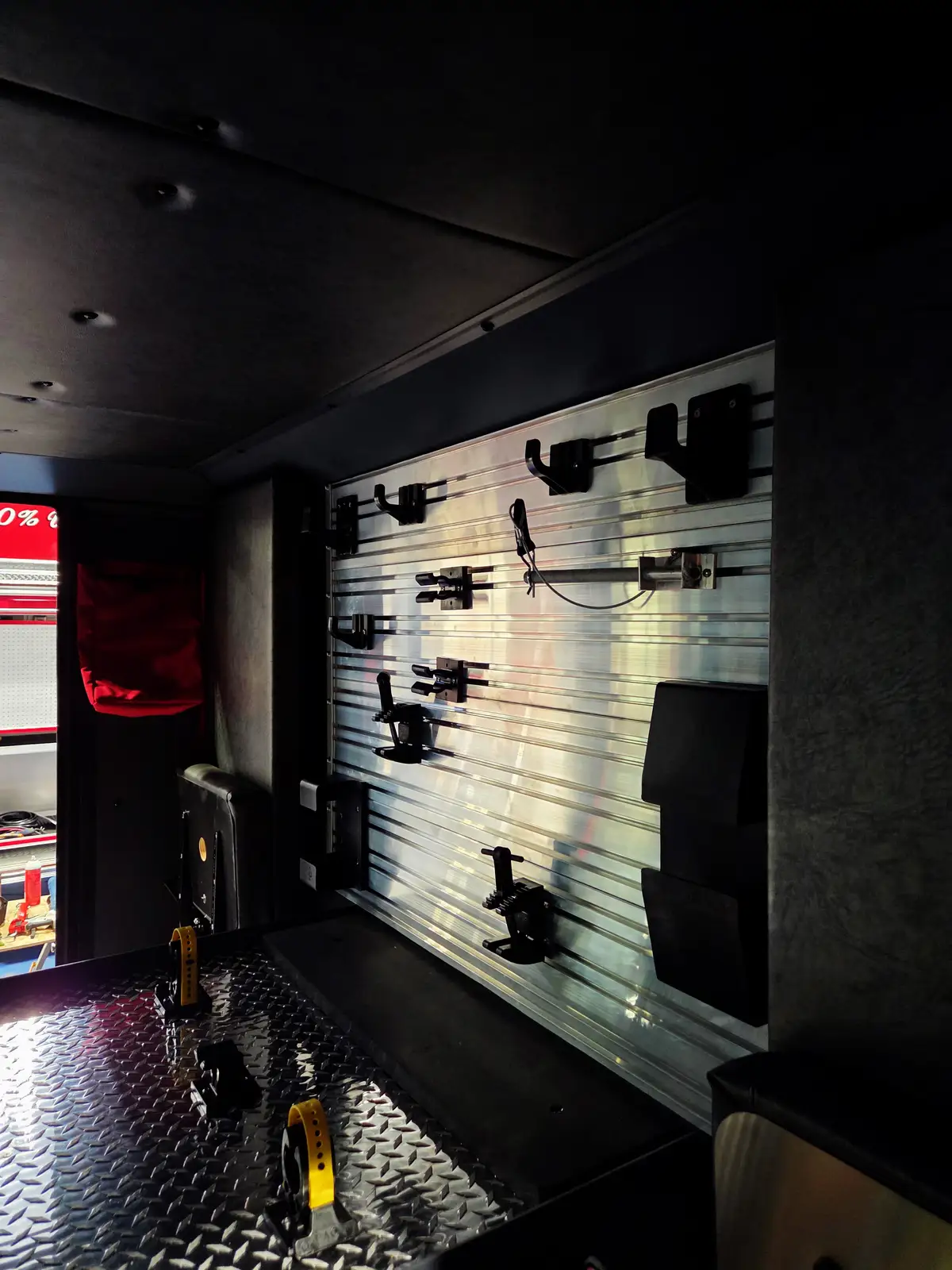 Dark equipment compartment interior showing wall-mounted brackets and tie-down points