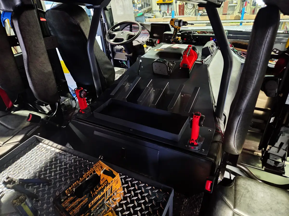 Cab interior rear-to-front view showing center console, steering wheel, and seat mounts