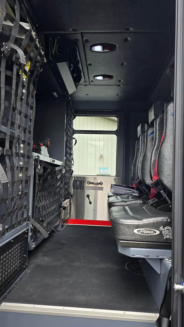 Rear crew compartment view showing bench seats, SCBA seat mounts, and hosebed netting