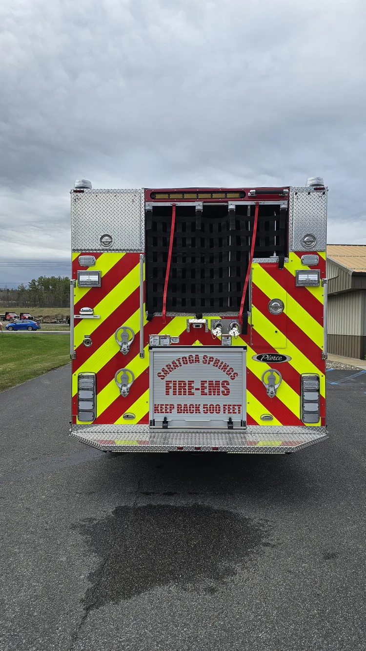 Rear view showing chevron striping, hosebed netting, and rear warning lights