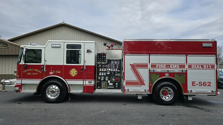 Pumper driver-side profile view showing pump panel, side compartments, and wheel area