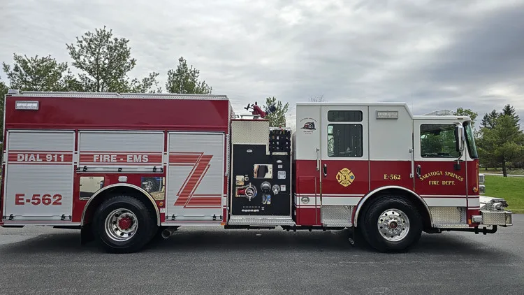 Pumper officer-side profile showing pump panel controls, side compartments, and rear wheel