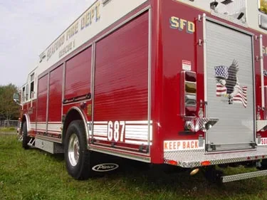 Rear-right exterior view showing rear body compartment, wheel area, and side striping