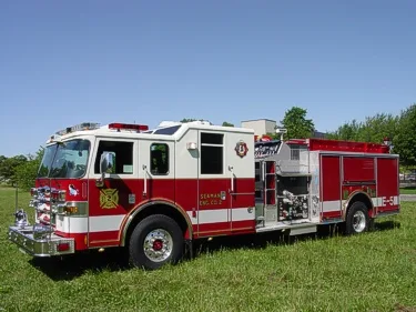 Front-right wide view showing the cab, pump panel controls, side compartments, and rear wheel area.