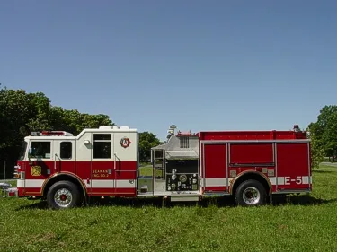 Driver-side profile showing the midship pump panel, side compartments, and full wheelbase.