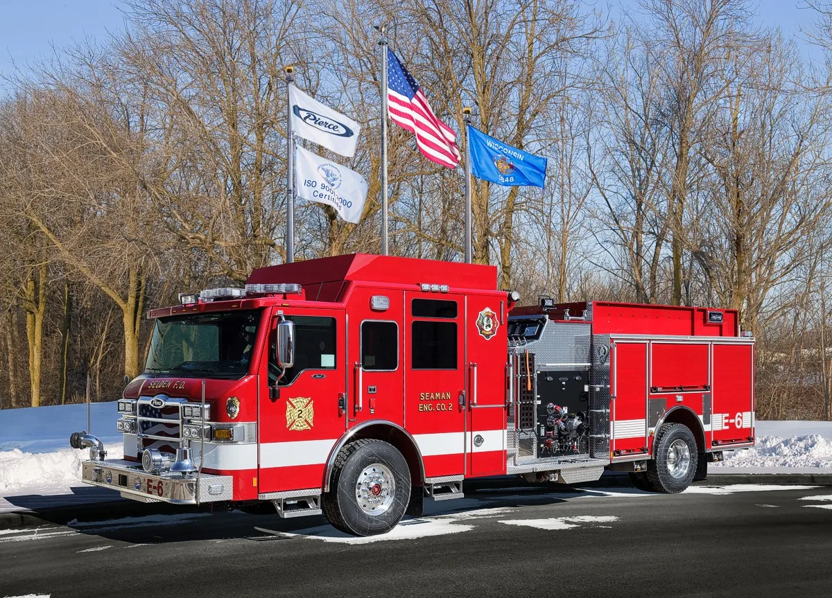 Front-left profile of a second red pumper showing side pump controls and rear body compartments.