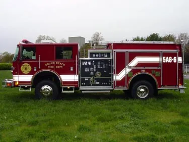 Driver-side profile view showing exposed pump panel, hose connections, and side compartments