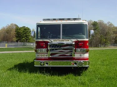 Head-on front view showing chrome bumper, grille, windshield, and roof warning lights.