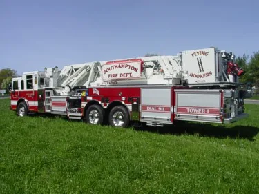 Rear right side view showing side compartments, tandem axles, and stowed aerial ladder sections.