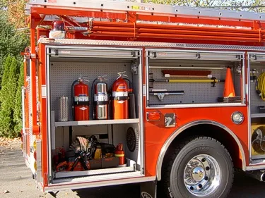 Rear-side compartment view showing fire extinguishers, tools, and wheel area