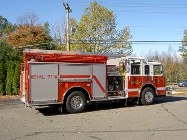Passenger-side profile view showing pumper body, rear compartments, and hose bed area