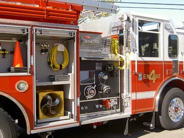 Driver-side compartment view showing hose reel, traffic cone, and pump-side controls
