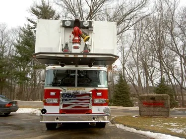 Head-on front view showing grille, bumper, warning lights, and bucket section above the cab.