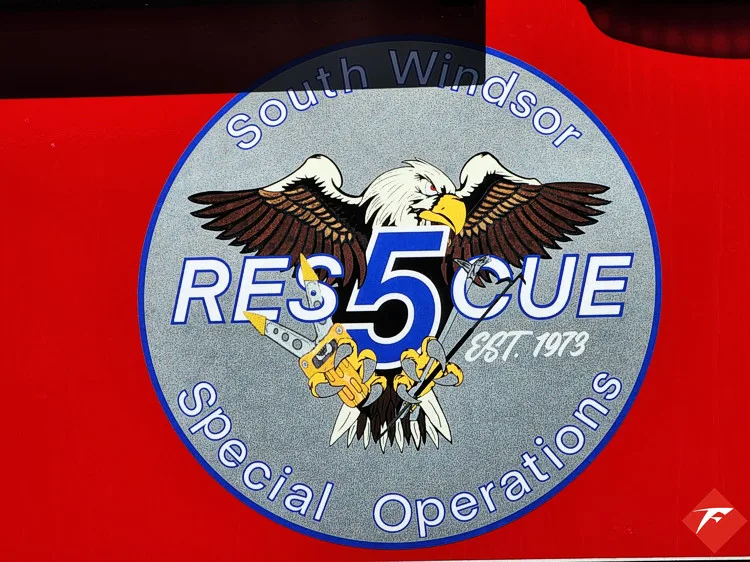 Body emblem close-up showing circular rescue crest on red panel