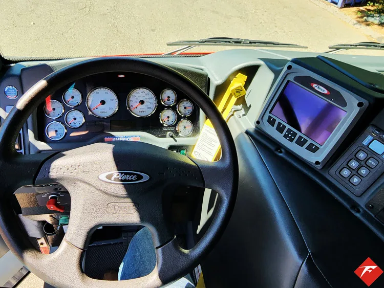 Driver cockpit view showing steering wheel, dash controls, and center monitor
