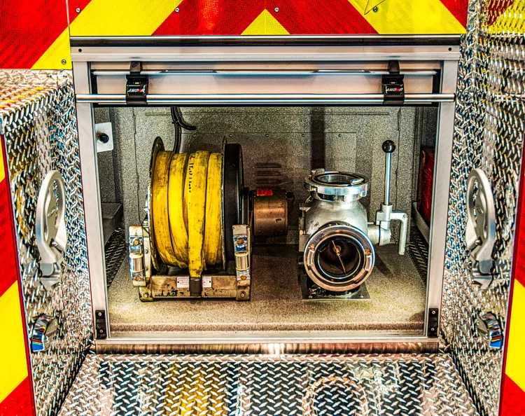 Rear compartment close-up showing coiled hose, large intake port, and compartment trim