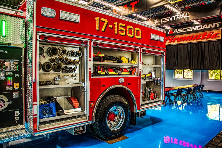 Driver-side compartments open showing tools, equipment trays, and rear wheel area