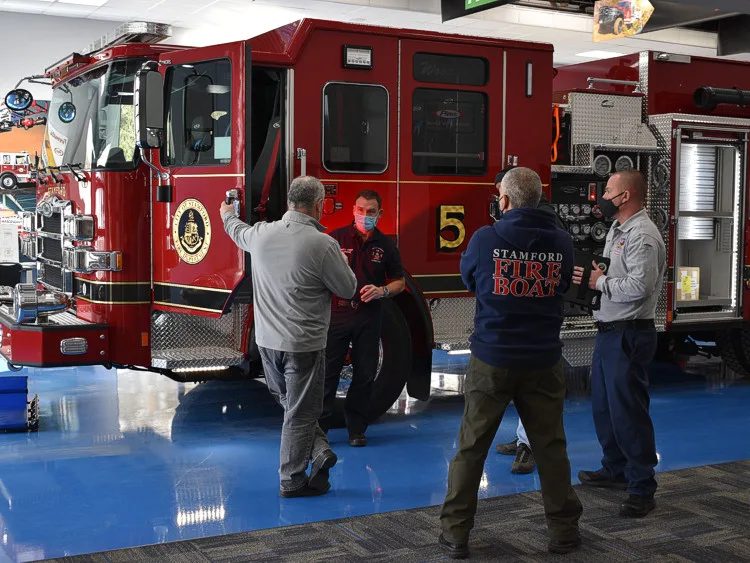 Front-left scene view showing pumper parked indoors with people nearby