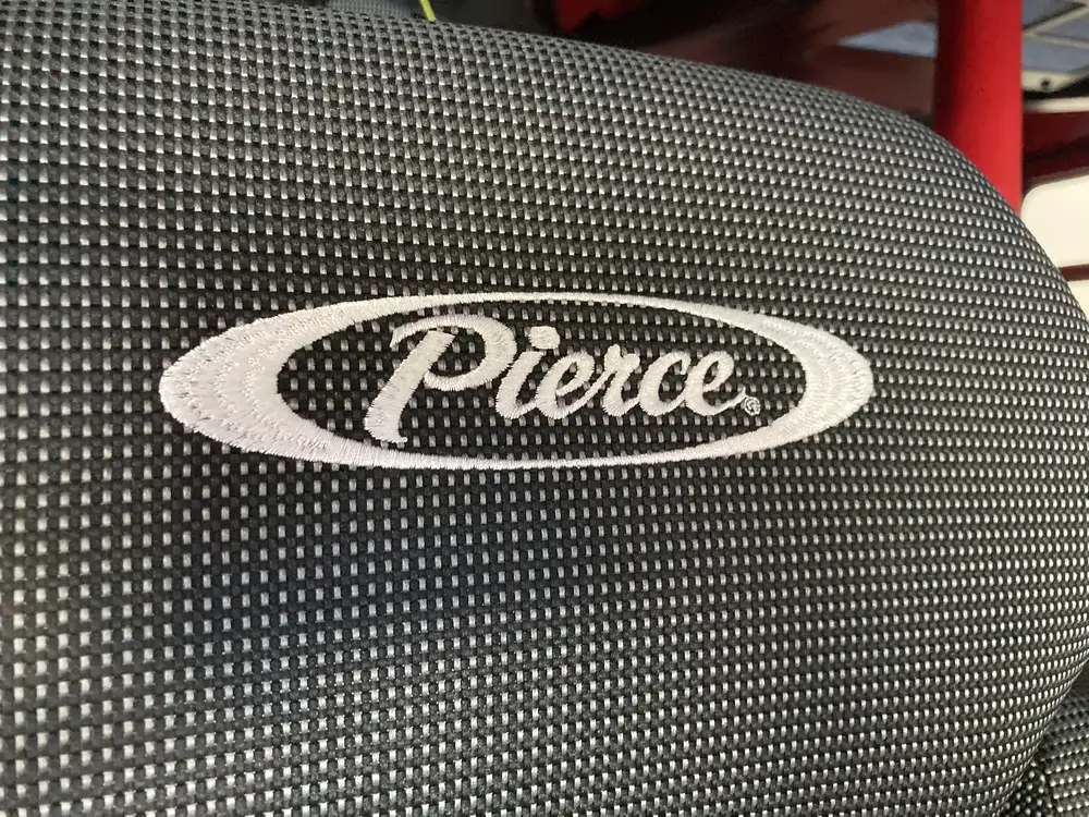 Seatback close-up showing Pierce logo on dark fabric