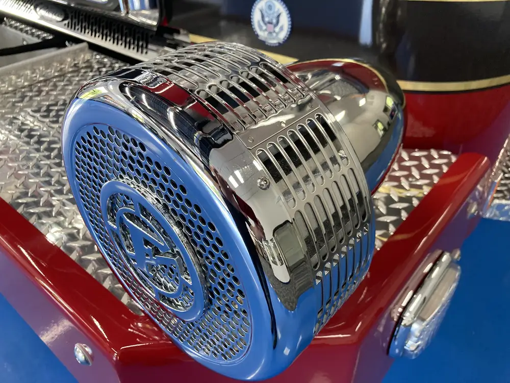 Bumper-mounted siren close-up showing blue grille and chrome housing