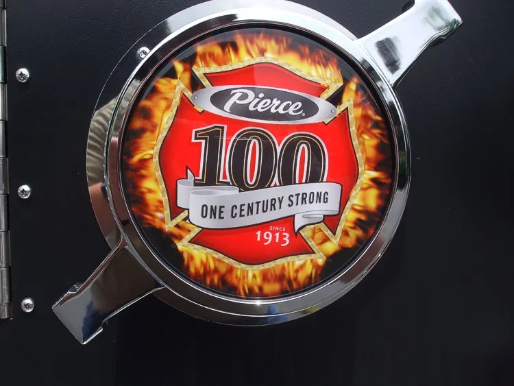 Round Pierce centennial emblem close-up on black pump panel surface