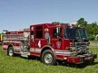 Pumper front-left exterior view on grass showing enclosed cab and side compartments