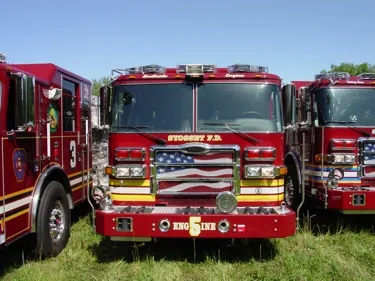 Front-quarter view of two pumpers showing grilles and warning lights