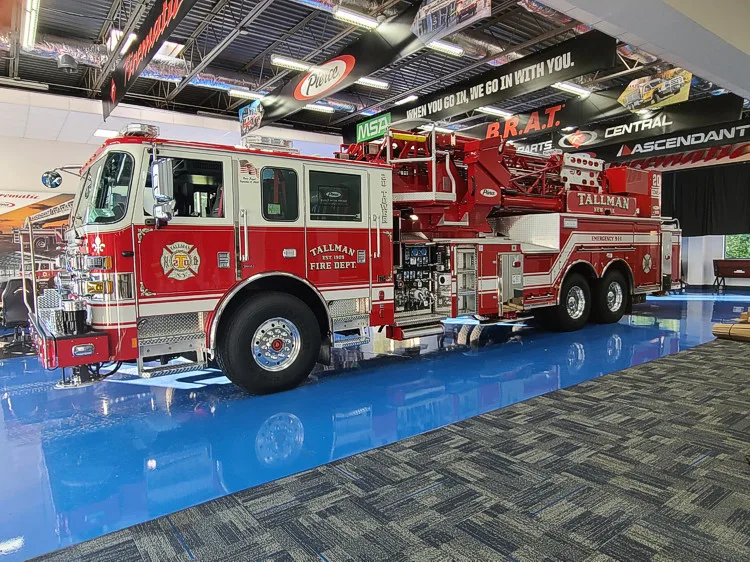 Tower ladder truck side profile view parked indoors on apparatus floor