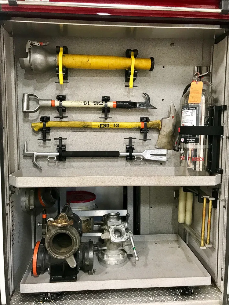 Open side compartment showing mounted hand tools and hose fittings