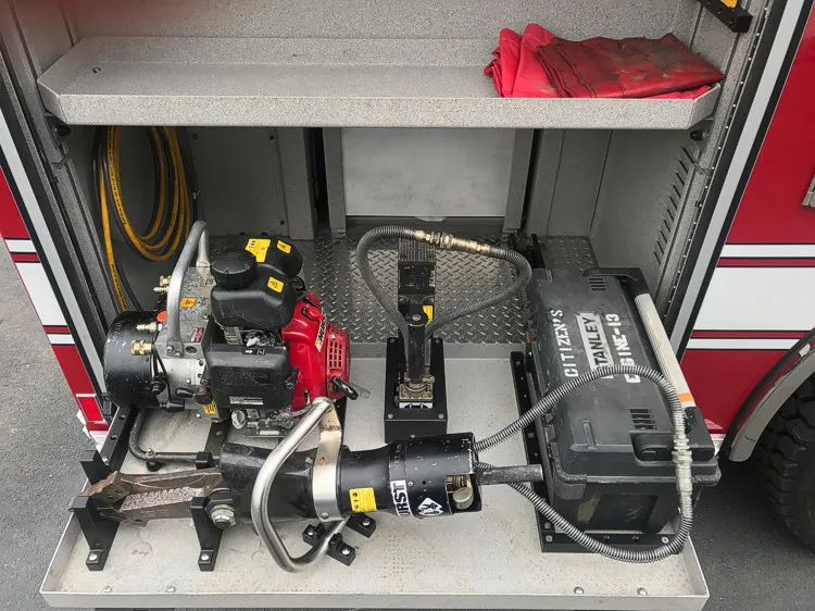 Open side compartment showing mounted rescue tool and hose connections