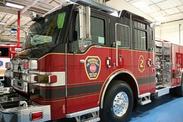 Close front left cab view showing door emblem, mirror, front wheel, and pump panel area behind the cab.